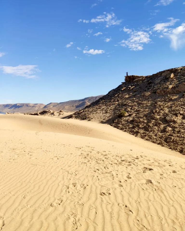 Frau im Kleid steht auf einer fernen Düne bei Agadir.