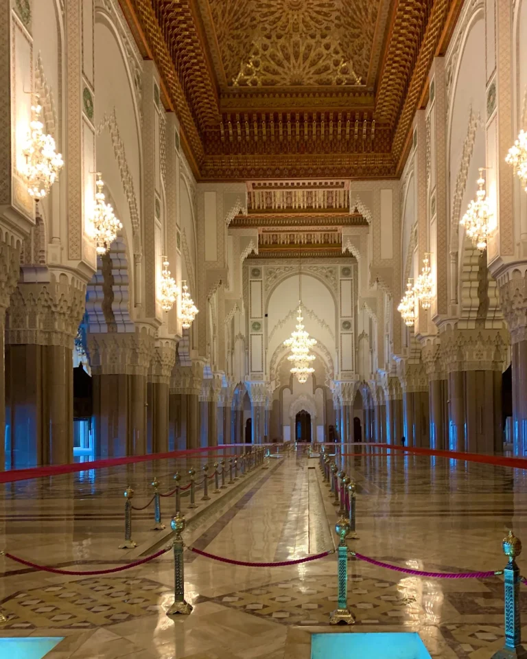 Prunkvoller Innenraum der Hassan-II.-Moschee mit Kronleuchtern, Holzdecke und verzierten Säulen.