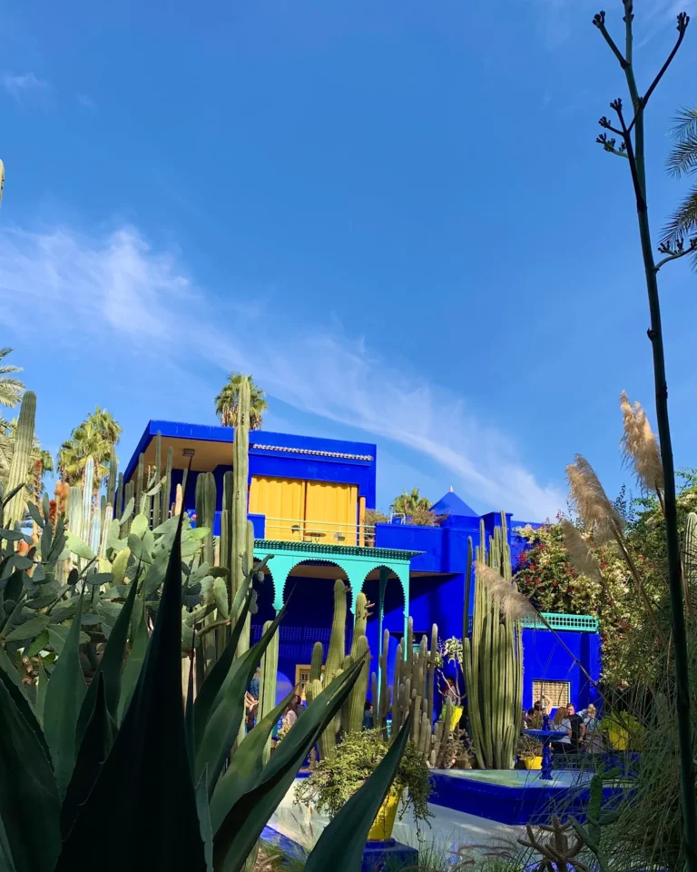 Kobaltblaues Gebäude im Jardin Majorelle mit gelben Akzenten und Kakteen.