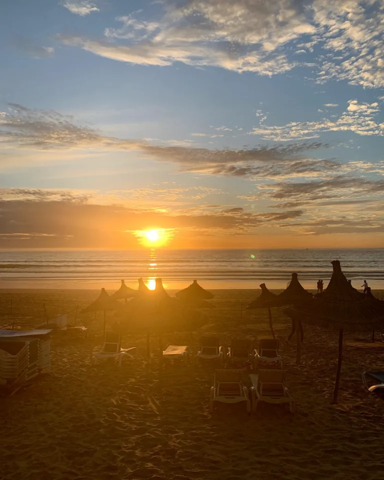 Sonnenuntergang am Strand von Agadir mit Strohschirmen.