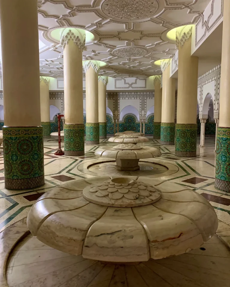 Waschraum der Hassan-II.-Moschee mit blütenförmigen Waschbecken und grünen Säulenverzierungen.