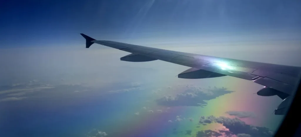 Blick aus dem Flugzeugfenster auf den Flügel und weiße Wolken während der Reise.
