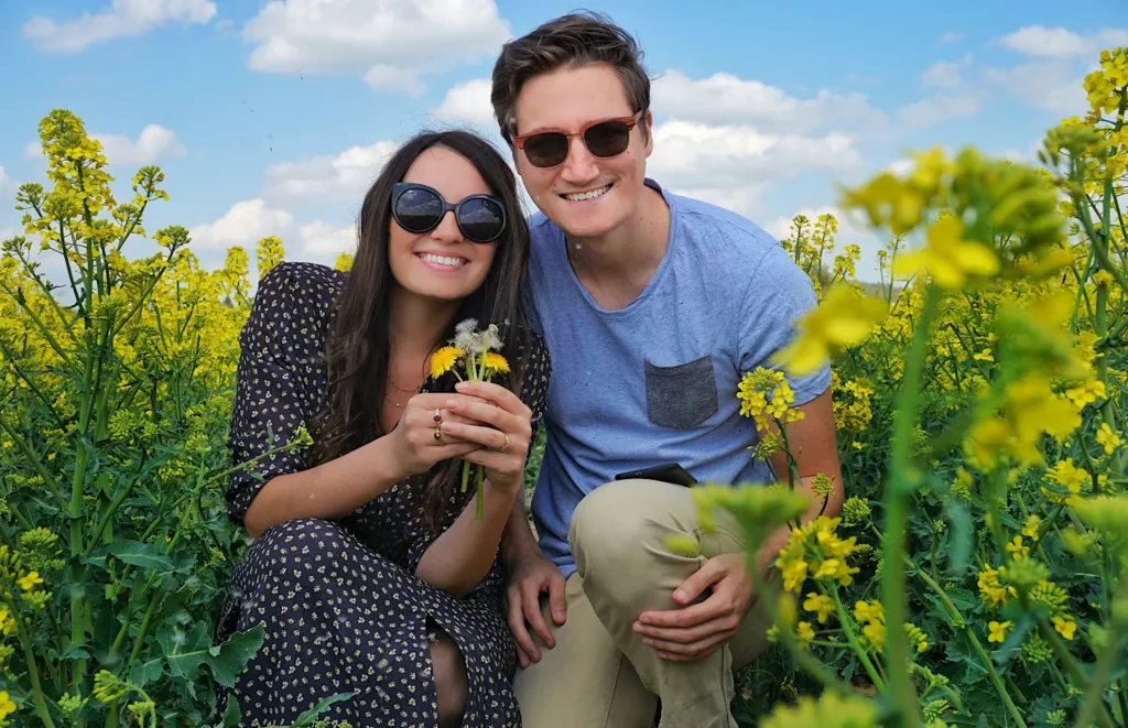 Close-up of a smiling couple wearing sunglasses in a yellow canola field in Germany.