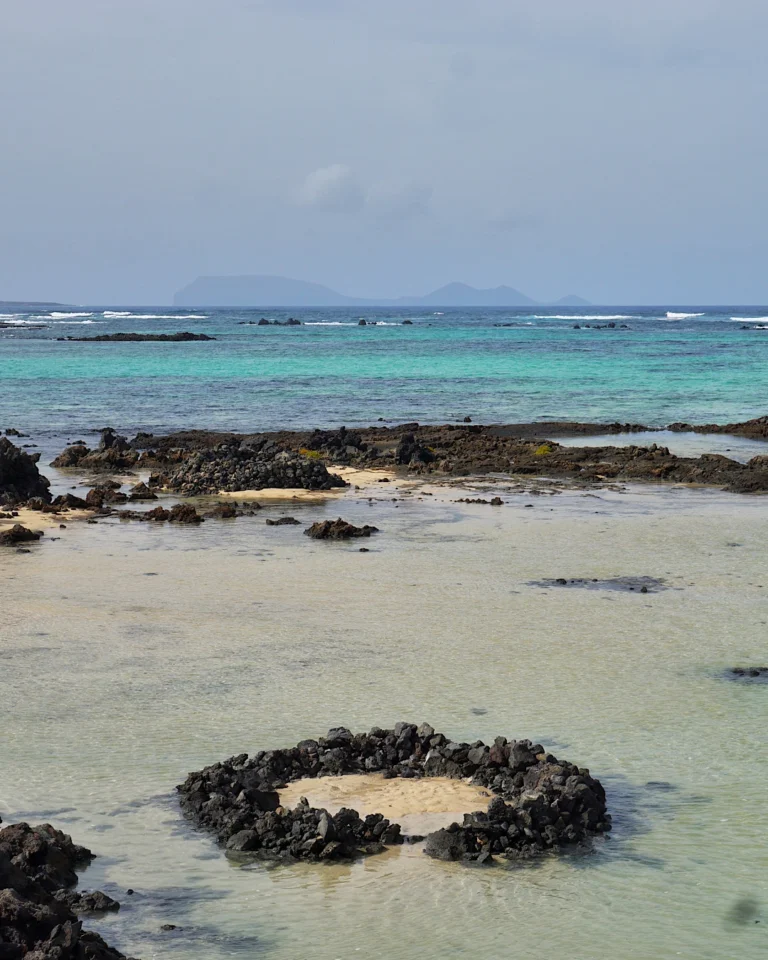 Weißer Sandstrand und schwarze Lavasteine am Badestrand Caletón Blanco auf Lanzarote.