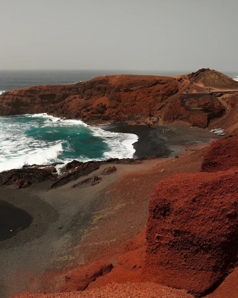 Der Strand von Lago Verde - El Golfo vor markanten roten Felsen auf Lanzarote.