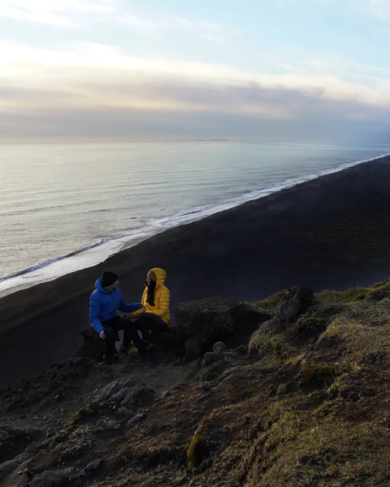 Us sitting atop Dyrhólaey, overlooking the black sand beach and dramatic cliffs of Iceland