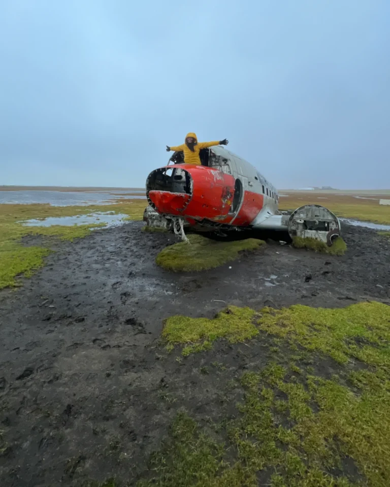 The wreckage of a red DC-3 plane at Eyvindarholt, surrounded by Iceland’s rugged landscape