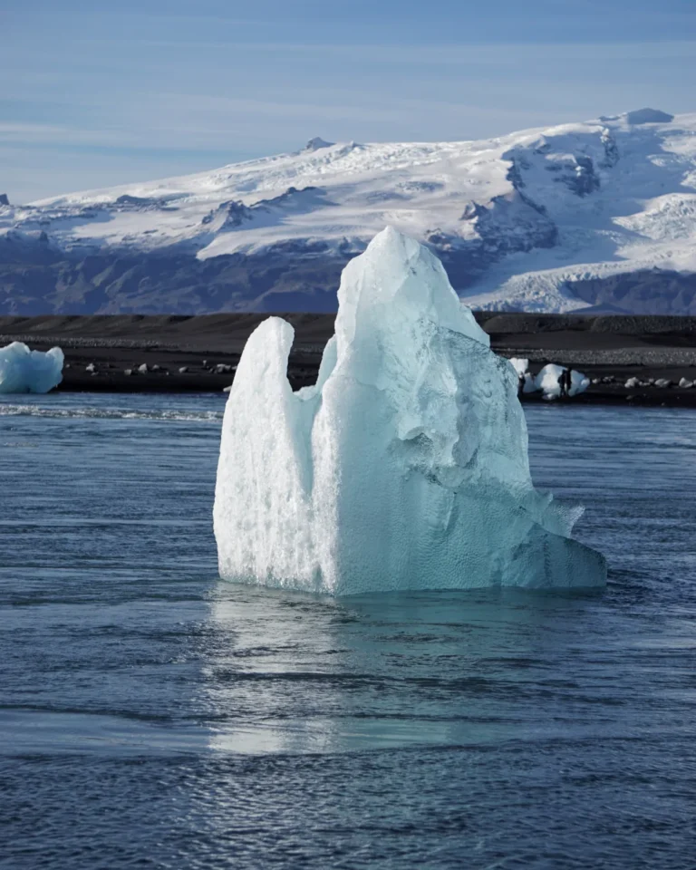 A small iceberg gently floating in the calm waters of Iceland, surrounded by natural beauty