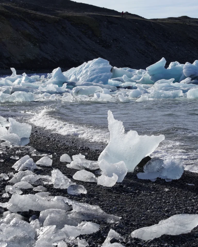 Ice chunks sparkling on Diamond Beach, with black volcanic sand shining in the sunlight, Iceland