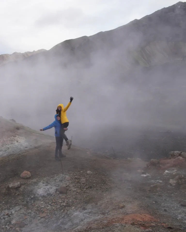 Us taking photographs amidst rising sulfur steam in the geothermal area of Landmannalaugar, Iceland