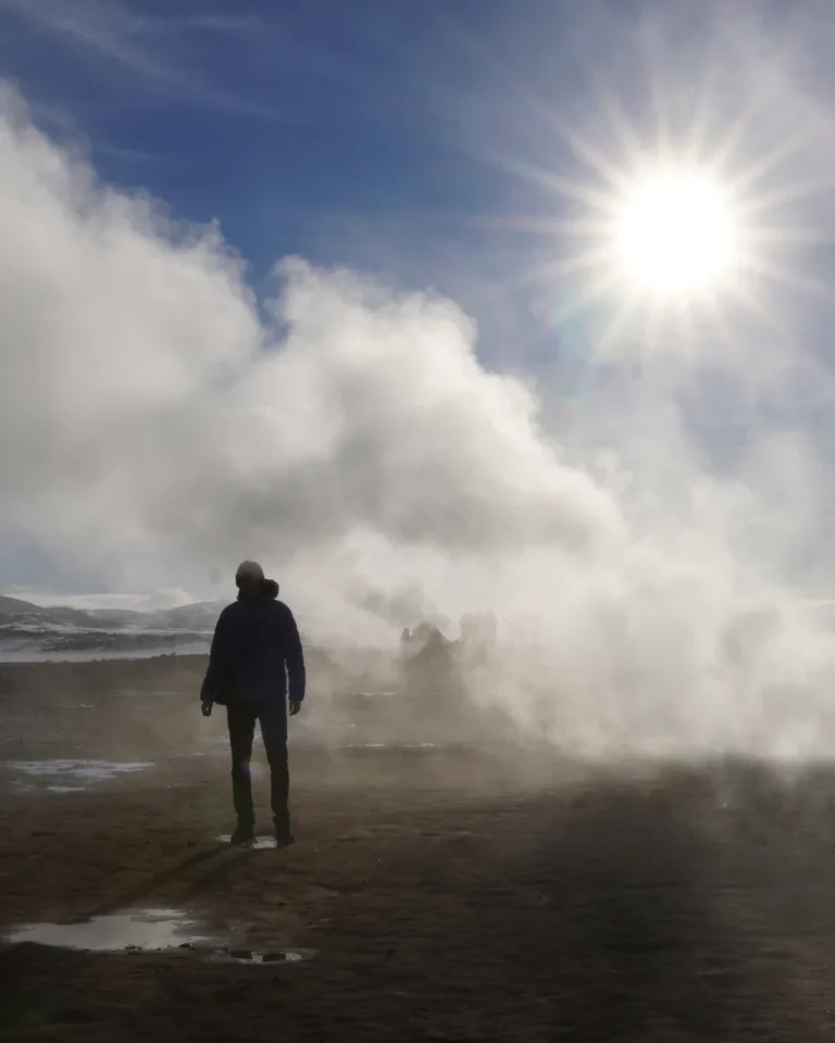 A person standing amidst the steam at Mývatn geothermal area, surrounded by geothermal features