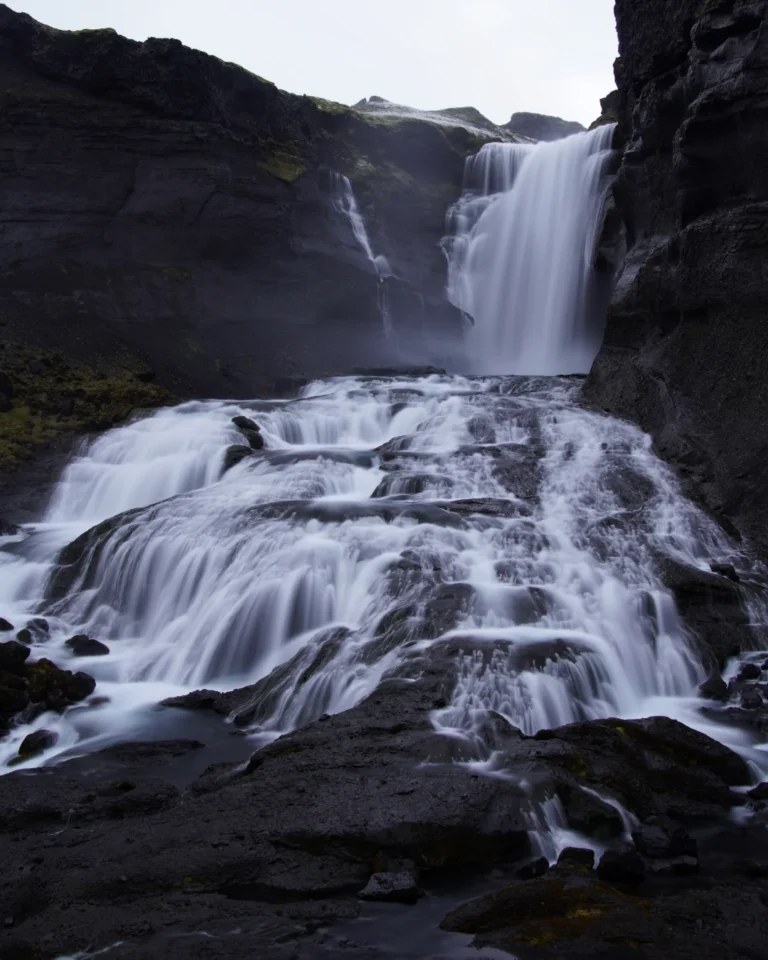 Wide angle shot of Ófærufoss waterfall from the middle viewing platform, showcasing its cascading flow and surrounding landscape, Iceland