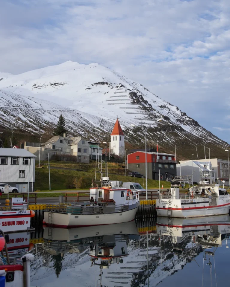 The harbour of Siglufjörður with a church and fishing vessels, surrounded by snow