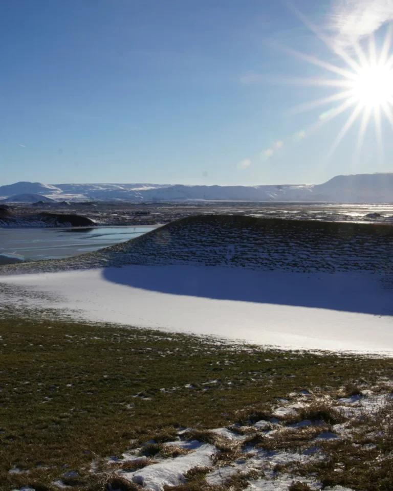 A sunny sky over Mývatn, Iceland, with a blanket of snow covering the ground and a clear blue sky above