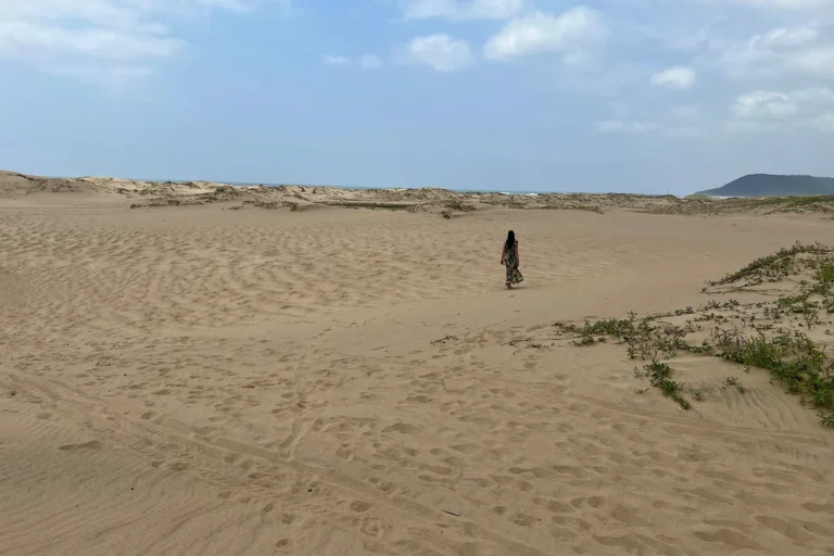 A woman walking through the sand dunes of St. Lucia during beautiful weather.