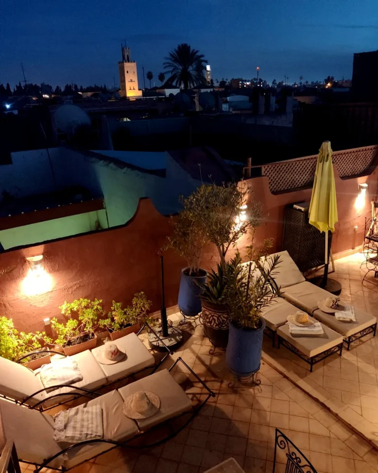 Illuminated rooftop terrace in Marrakech at night with a view of a minaret.