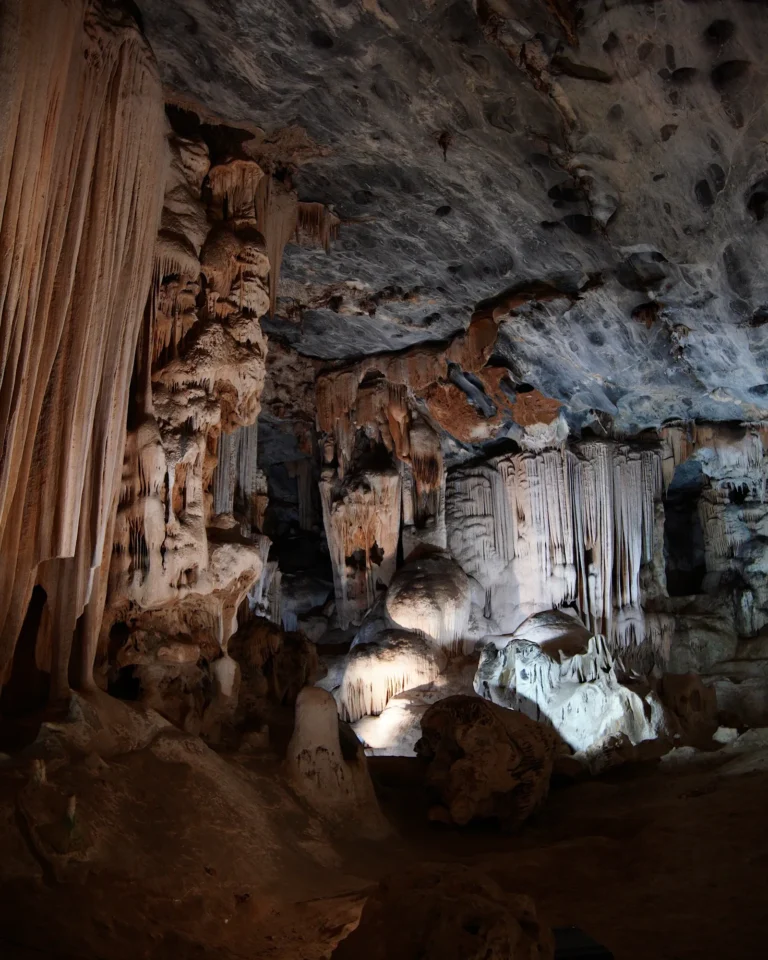 Interior view of the Cango Caves showing illuminated dripstones and stalactites.