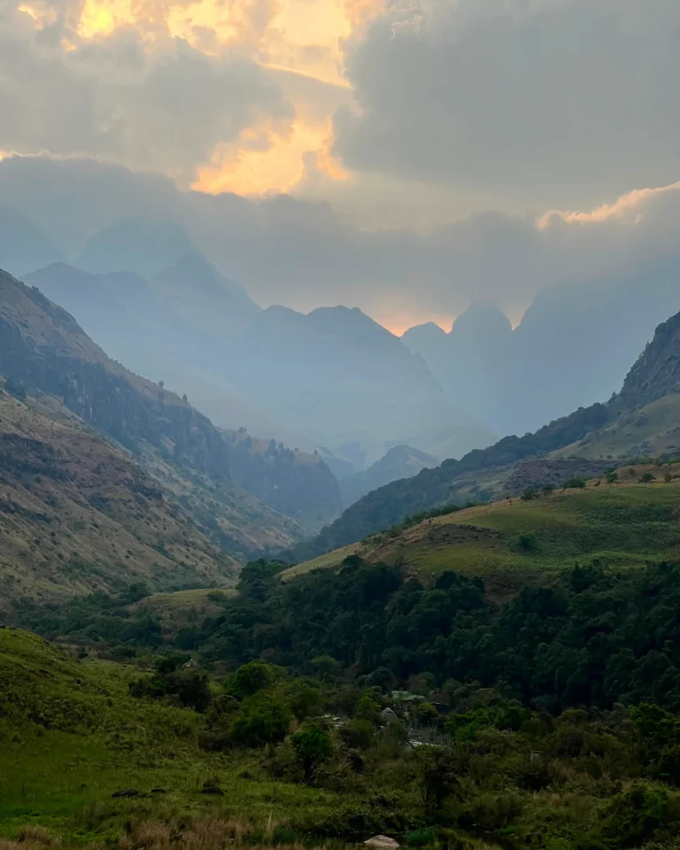 The peaks of Cathedral Peak in the Drakensberg during a misty sunset.
