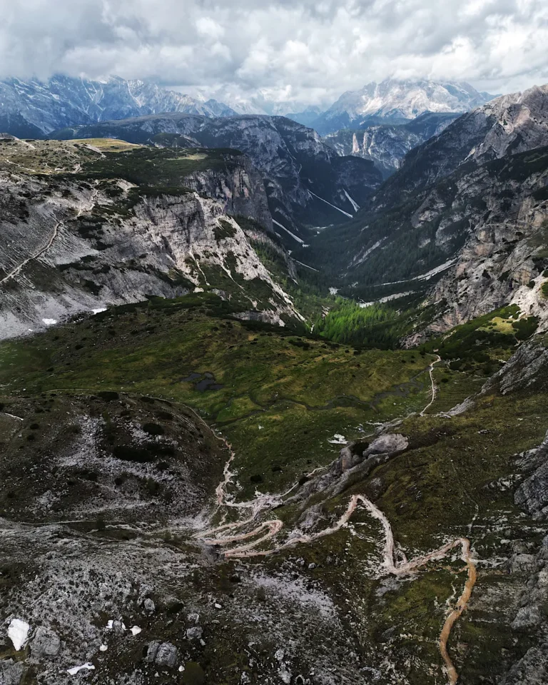 High-angle view of winding hiking trails in a deep valley within the Dolomites.