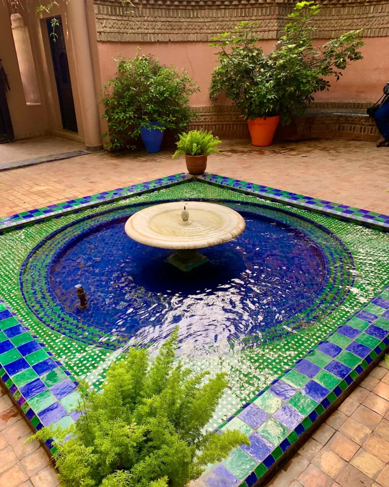 Blue and green mosaic fountain in the Jardin Majorelle courtyard.