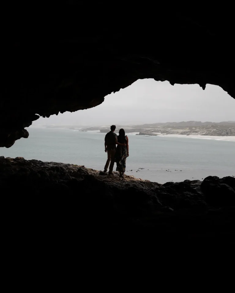 View from inside Klipgat Cave towards the sea with travel couple silhouettes in the center.