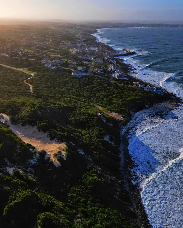 Drone photo of green sand dunes, houses, and the sea in Kenton-on-Sea.
