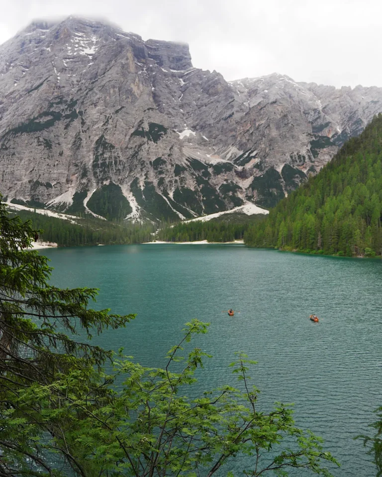 Blick auf das klare, dunkelblaue Wasser des Pragser Wildsees umrahmt von grünen Nadelwäldern.