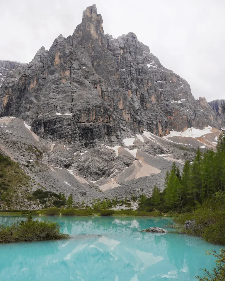 The turquoise Lake Sorapis in the Dolomites with the iconic Dito di Dio mountain peak in the background.