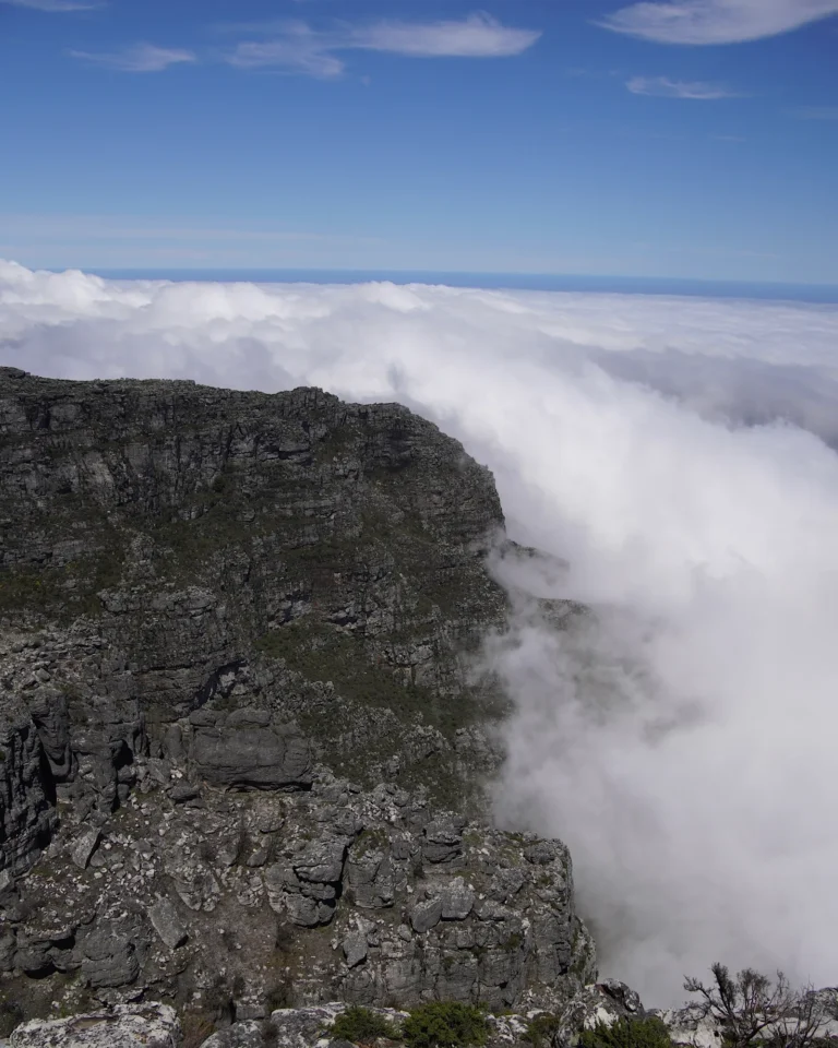 Rocky terrain on Table Mountain summit covered in thick white clouds.