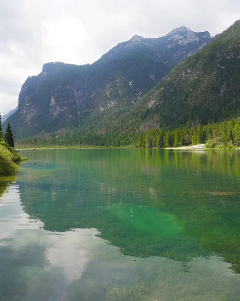 Der ruhige Toblacher See spiegelt die umliegenden bewaldeten Berge unter einem weiten Himmel wider.
