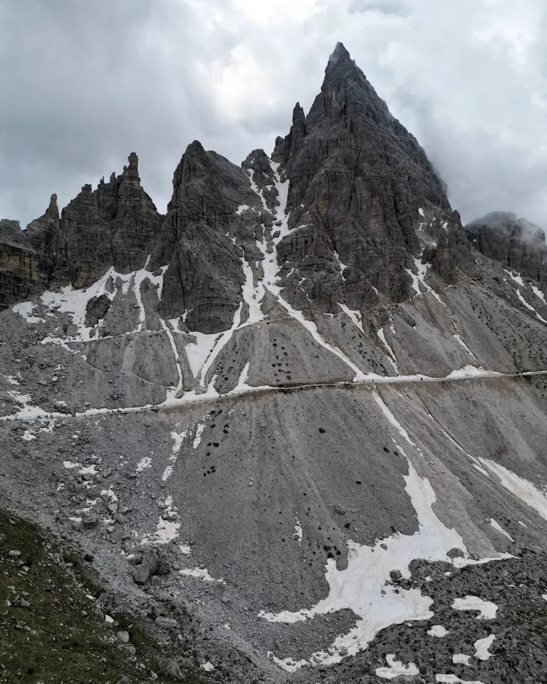 A narrow hiking path winding through scree slopes below the Paternkofel mountain in the Dolomites.