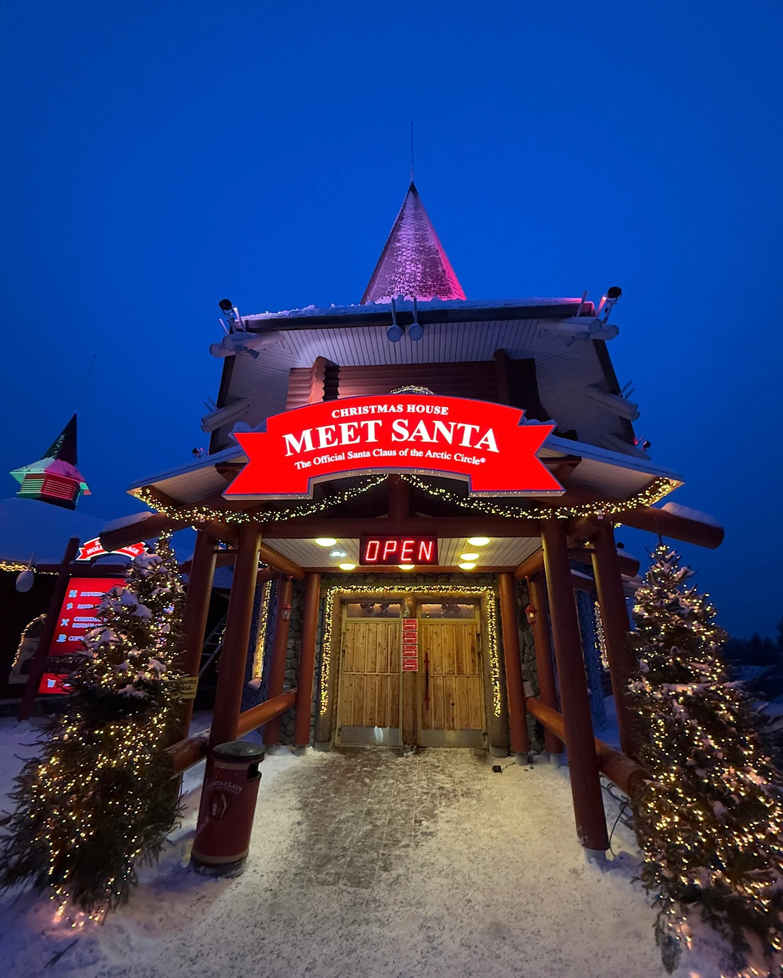Außenansicht des beleuchteten Hauses vom Weihnachtsmann (Meet Santa) am Abend in Rovaniemi.
