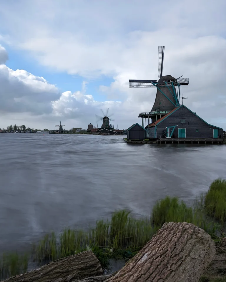 Panorama-Blick auf mehrere historische Windmühlen am Ufer des Flusses Zaan in der Zaanse Schans.