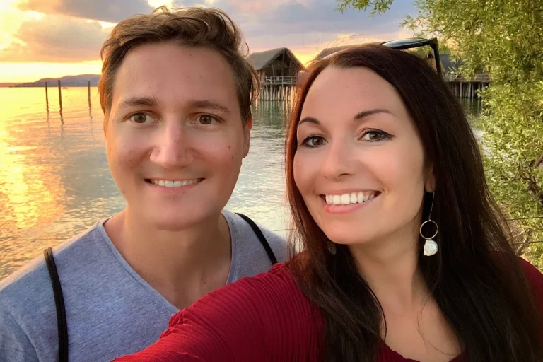 Selfie eines Paares vor den Pfahlbauten in Unteruhldingen am Bodensee bei Sonnenuntergang.
