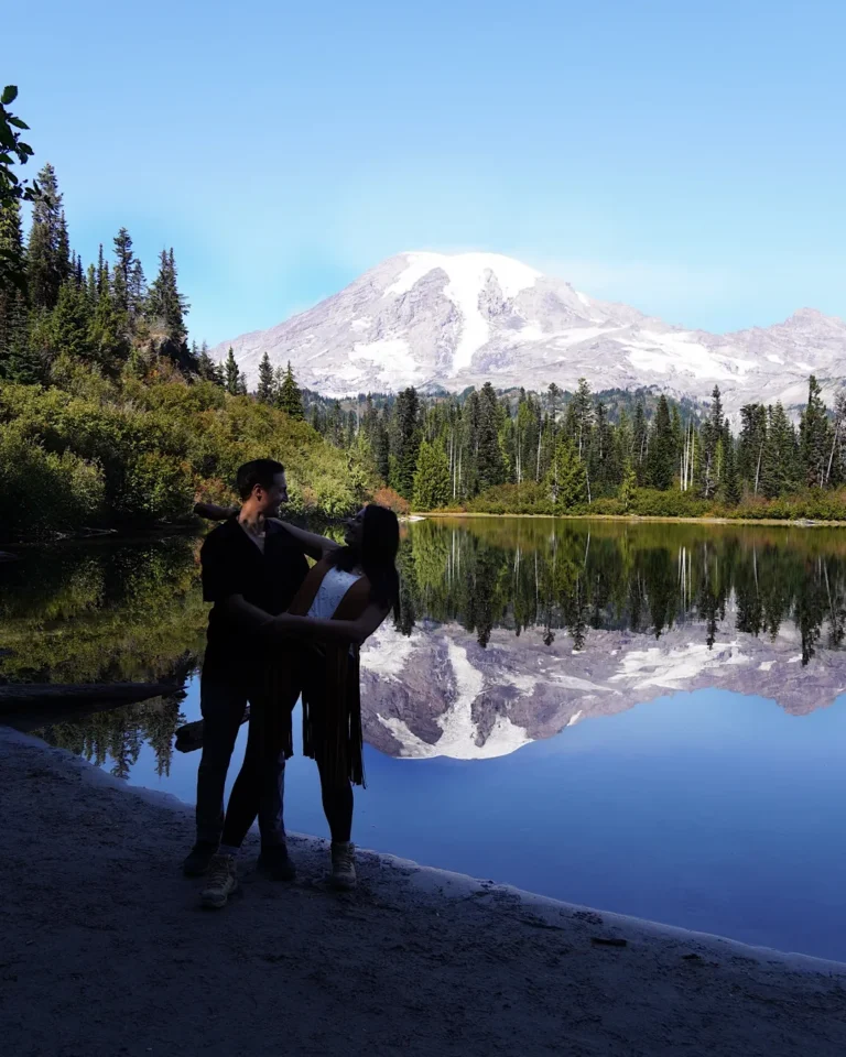 Ein tanzendes Paar am Ufer eines Sees mit der Spiegelung des Mount Rainier.