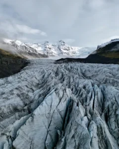 Drohnenaufnahme des Vatnajökull Gletschers in Island mit tiefen Gletscherspalten und Bergen.