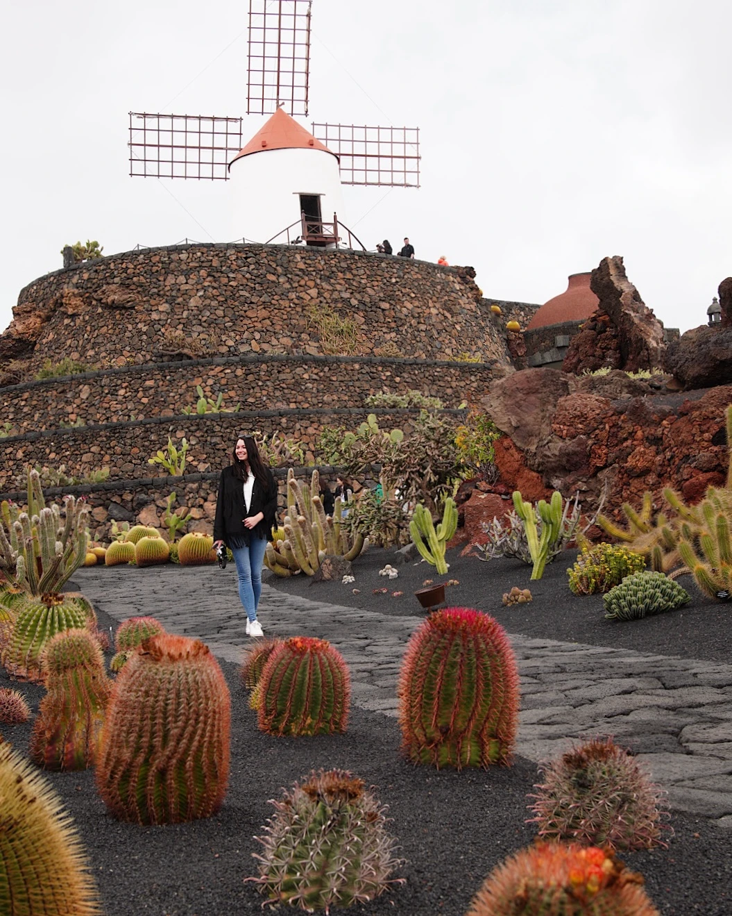 A woman walking on a paved path through the Cactus Garden of Lanzarote.