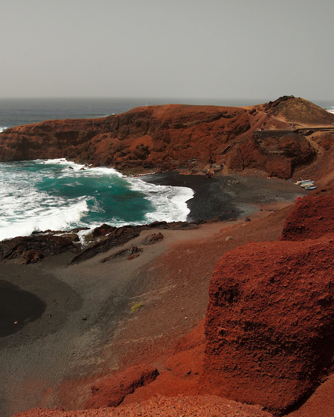 The blue ocean of Lago Verde at El Golfo beach in front of striking red rocks in Lanzarote.