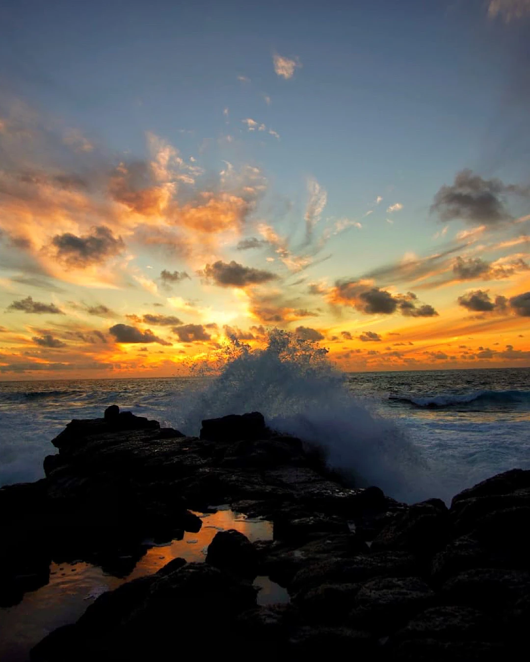 Romantic sunset at the rocky coast of La Isleta, Lanzarote, with crashing waves.