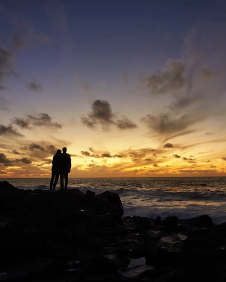 Couple watching the romantic sunset over the ocean at La Isleta, Lanzarote.