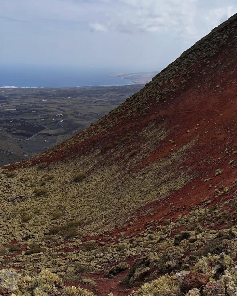 View into the deep red volcanic crater from the summit of Volcán de la Corona, Lanzarote.